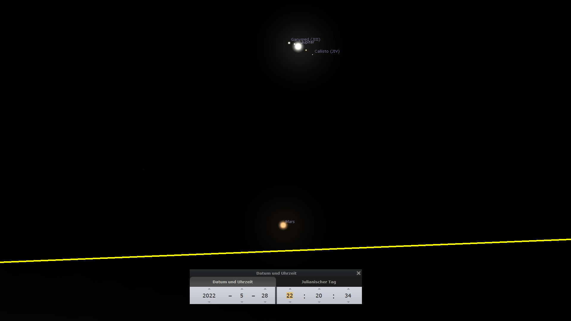 Eine astronomische Darstellung zeigt den Planeten Jupiter mit seinen drei großen Monden Ganymed, Jupiter selbst und Kallisto vor einem schwarzen Hintergrund. Links unten ist der Planet Mars sichtbar. Ein gelber Strich markiert die Ekliptik. Die Navigationsleiste unten zeigt das Datum und die Uhrzeit vom 28. Mai 2022, 22:20:34 Uhr, sowie den Julianischen Tag.