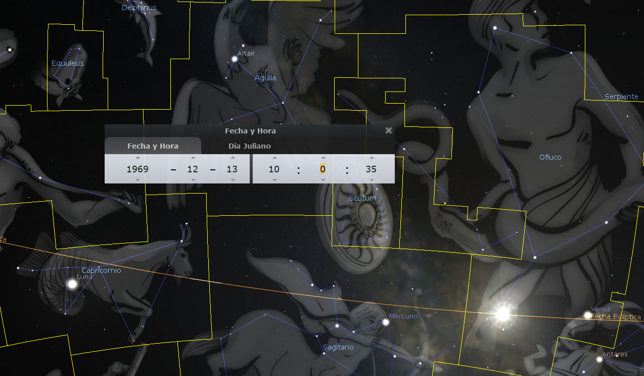 Imagen de un mapa estelar que muestra varias constelaciones y cuerpos celestes, con superposiciones que etiquetan los nombres de las constelaciones, planetas como Mercurio y Venus, y la posición del Sol. Una interfaz en la pantalla muestra "Fecha y Hora" con valores ajustados al 13 de diciembre de 1969, y el "Día Juliano". El fondo es un espacio oscuro salpicado de estrellas.